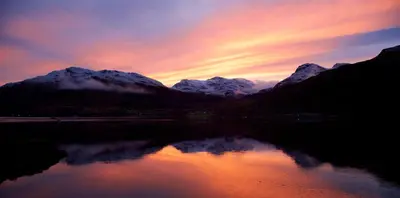 a sunset over a lake with snow covered mountains at No 2 Planetree in Lochgoilhead