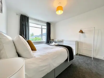 a bedroom with a large white bed with a window at Kingsbridge Apartment in Glasgow