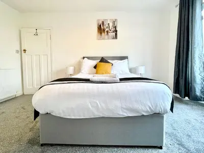 a bedroom with a large bed with white sheets and yellow pillows at Kingsbridge Apartment in Glasgow