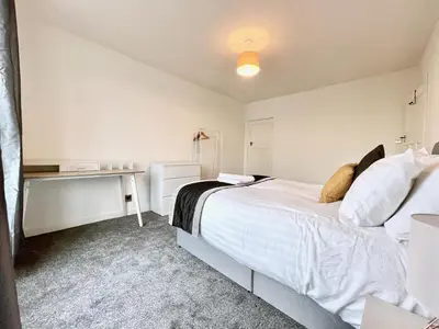 a bedroom with a large white bed and a desk at Kingsbridge Apartment in Glasgow