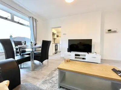 a living room with a television and a table with chairs at Kingsbridge Apartment in Glasgow