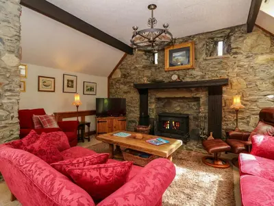 a living room with red furniture and a stone fireplace at The Steading in Dalmally