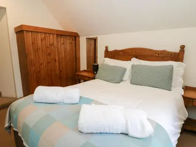 a bedroom with a large white bed with towels on it at The Steading in Dalmally