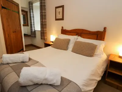 a bedroom with a large white bed with two lamps at The Steading in Dalmally