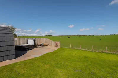 a backyard with a bench and a fence and a field at The Stag Pod Farm Stay with Hot Tub Sleeps 2 in Galston