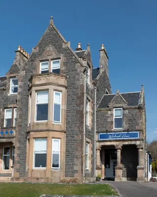 an old brick building with a sign on it at Witchwood House in Oban