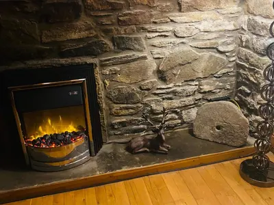 a stone fireplace in a room with a stone wall at Mawenyoupe in Lochgilphead