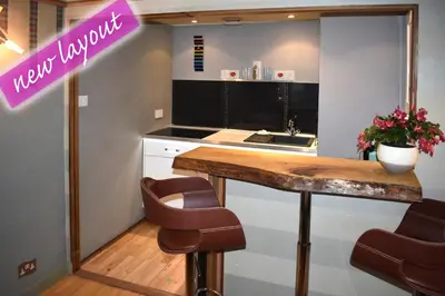 a kitchen with a counter with chairs and a table at The Retreat Tranquil Countryside Apartment in Larkhall