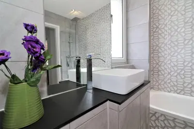 a bathroom with a sink and a vase with purple flowers at Macintosh Upper in Bellshill