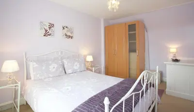 a bedroom with a white bed and a wooden cabinet at Avonlea Self-Catering in Crieff