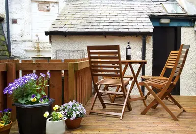 two chairs and a table on a deck with flowers at Avonlea Self-Catering in Crieff