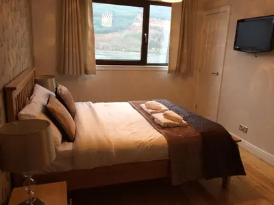 a bedroom with a bed with two towels on it at Ben Arthur's Bothy Luxury Flat in Arrochar