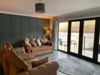 a living room with two couches and a balcony at Ben Arthur's Bothy Luxury Flat in Arrochar