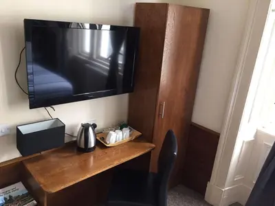 a room with a desk with a television on a wall at Glasgow House in Glasgow