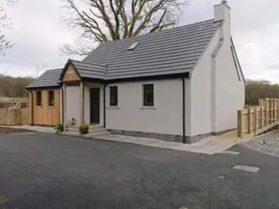 a small white house with a black roof at Clarinnes Cottage in Rowardennan