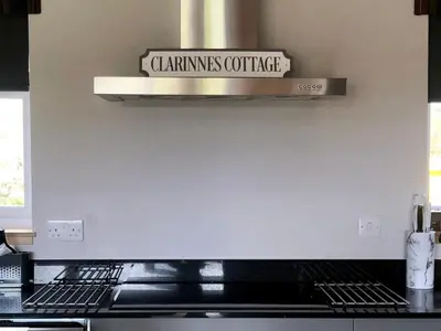 a sign on a wall above a stove in a kitchen at Clarinnes Cottage in Rowardennan
