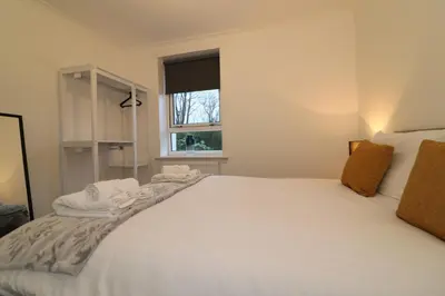 a bedroom with a large white bed with a window at Signature - Carrick View in Cumbernauld