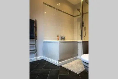 a bathroom with a shower and a bath tub at Struan Coach house in gated residence in Stirling