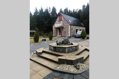 a building with a fountain in a parking lot at Struan Coach house in gated residence in Stirling