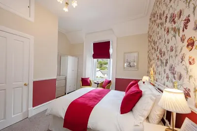 a bedroom with a large bed with red accents at Hawthornbank in Oban