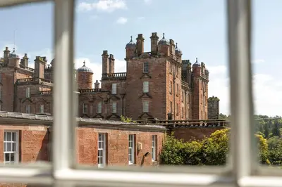 a view of a large castle from a window at Stableyard Studio: Drumlanrig Castle in Thornhill