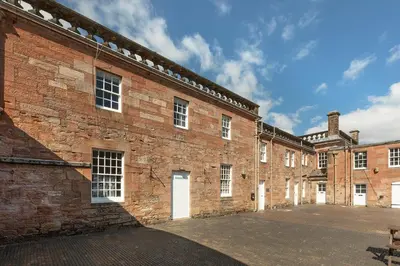 a large brick building with white doors and windows at Stableyard Studio: Drumlanrig Castle in Thornhill