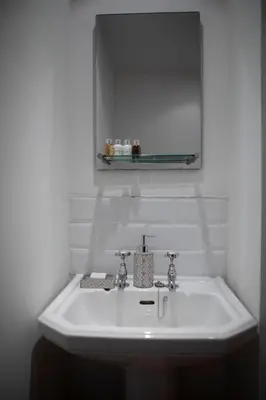 a white sink in a bathroom with a mirror at Drumlanrig Mains Cottage in Thornhill