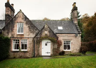an old stone house with a white door at Drumlanrig Mains Cottage in Thornhill