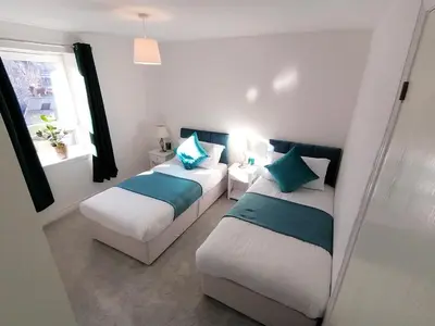 a bedroom with two beds and a window at Seaside Apartment in Oban