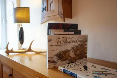 a book sitting on a table next to a lamp at Kentraw Farmhouse Luxury Self Catering in Bruichladdich