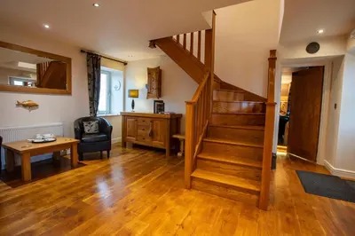 a living room with wooden floors and a staircase at Kentraw Farmhouse Luxury Self Catering in Bruichladdich