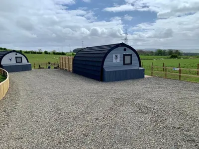 a couple of blue storage sheds in a field at Thistle Pod Farm Stay with Hottub Sleeps 2 in Galston