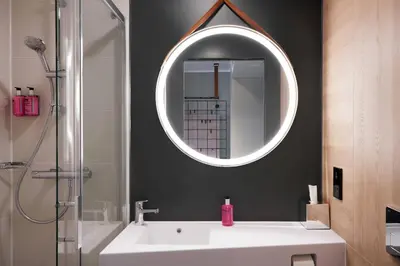 a bathroom with a white sink and a mirror at Moxy Edinburgh Fountainbridge in Edinburgh