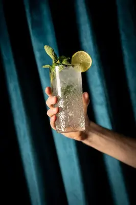 a hand holding a drink with a lime on it at Moxy Edinburgh Fountainbridge in Edinburgh