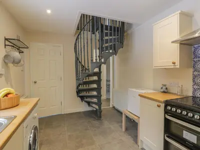 a kitchen with a spiral staircase in a house at Maisie's Cottage in Dunblane