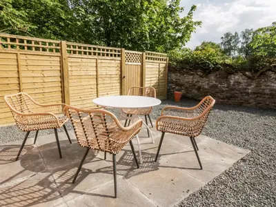 a table and four chairs and a table and a fence at Maisie's Cottage in Dunblane