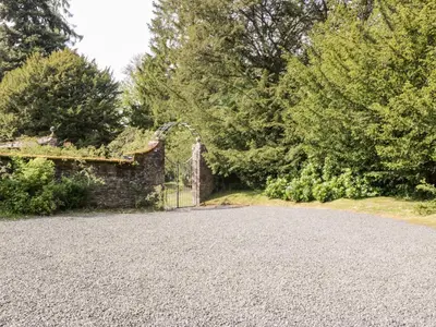 a stone driveway with a gate and trees at Maisie's Cottage in Dunblane