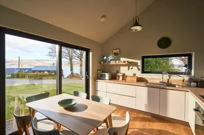 a kitchen with a table and a large window at An Airigh in Cairndow