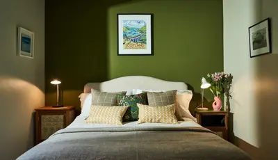 a bedroom with a large bed with green walls at An Airigh in Cairndow