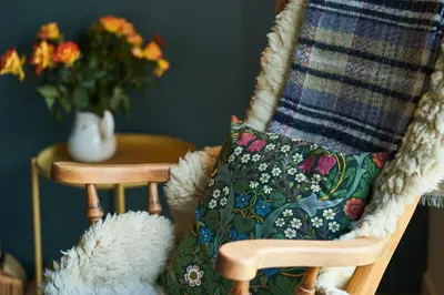 a pillow sitting on a chair with a vase of flowers at An Airigh in Cairndow