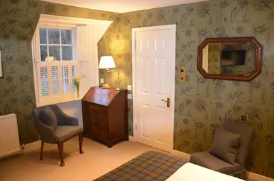 a bedroom with a desk and a chair and a mirror at The Manor House in Oban