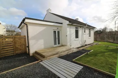 a small white house with a wooden deck at Signature - Railway Cottage in Maryhill