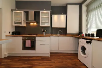 a kitchen with white cabinets and a washing machine at Signature - Railway Cottage in Maryhill