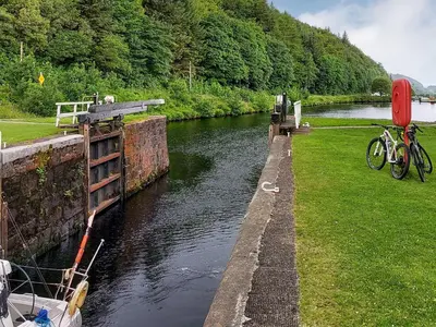a boat is docked next to a canal with trees at Ar Deireadh in Tayvallich