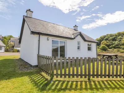 a small white house with a wooden fence at Ar Deireadh in Tayvallich