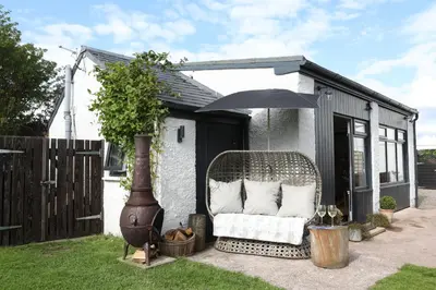 a wicker chair sitting in a yard next to a shed at Garden Studio in Biggar in Biggar