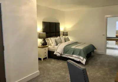a bedroom with a bed and a table and a chair at East Church House, Unique 9 bedroom Church, Historic Market Town. in Strathaven