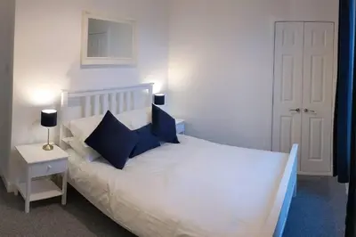 a bedroom with a white bed with blue pillows at Glenfinnan - Two Bedroom Apartment in Fife