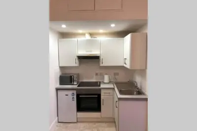 a small kitchen with white cabinets and a sink at Glenfinnan - Two Bedroom Apartment in Fife