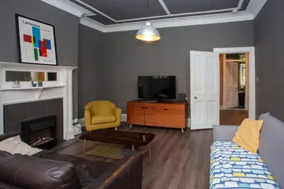 a living room with a couch and a tv at Modern, Light-filled and Sleek West End Apartment in Glasgow